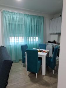 a kitchen with a table and blue chairs and a table and a table and chairs at Apartman Jass in Stari Banovci +28 photos