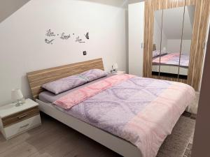 a bedroom with a large bed and a mirror at Apartmani G&E in Delnice