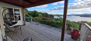 a deck with chairs and a view of the water at Pureanei in Rawene