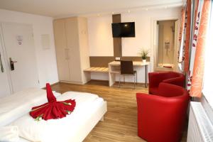 ネルトリンゲンにあるGoldener Schlüssel mit Gästehaus Sinaのベッドと赤い椅子が備わるホテルルームです。