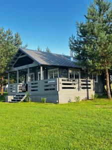 a house with a porch and a green lawn at Kregžlės slėnis in Skirlėnai