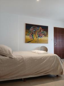 a bedroom with a bed and a painting on the wall at Punto Sur Apart in Río Cuarto