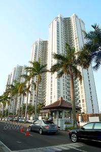 een groot gebouw met palmbomen ervoor bij The Residences at Puri Casablanca in Jakarta