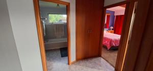 a bathroom with a mirror and a bedroom with a bed at Pureanei in Rawene