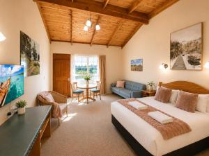a bedroom with a large bed and a living room at Coonawarra Place Motor Inn in Coonawarra