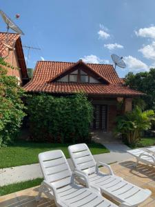 two white lounge chairs in front of a house at Chalé Gravatá 2022 in Gravatá