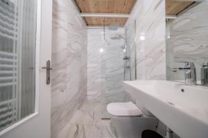 a white bathroom with a toilet and a sink at Meraki Seaside Suite Pelion in Kalamos +16 photos