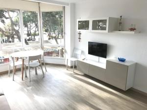 a white living room with a table and a tv at La mestrança in Blanes