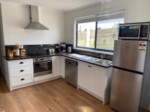 a kitchen with a stainless steel refrigerator and a window at Oak Vue cottage in Korumburra