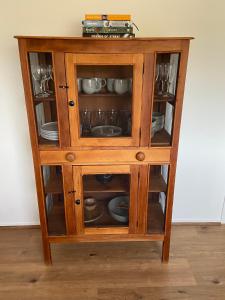 a wooden cabinet with plates and dishes in it at Oak Vue cottage in Korumburra