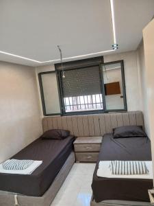 a small bedroom with two beds and a window at Ikamat raha in Tangier