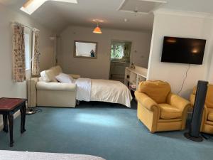 a bedroom with a bed and a couch and a chair at Hidden cottage in Abingdon
