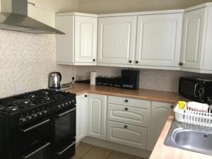 a kitchen with white cabinets and a black stove top oven at Llandudno holiday home in Llandudno