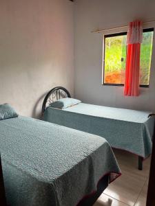 two beds in a room with a window at Aconchego Da Serra in Triunfo