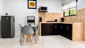 a kitchen with a refrigerator and a table and chairs at Rio Celeste Birds Garden Apartments with air conditioning and Wifi Starlink in Upala