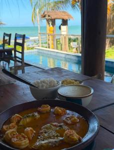 a table with a bowl of shrimp and rice next to a pool at Club Manguaba Beira Mar in Japaratinga