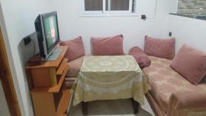 a living room with a couch with a table and a tv at Tamawnza in Aourir