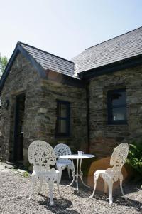 three chairs and a table in front of a building at Shiplake Mountain Farmhouse in Dunmanway