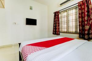 a bedroom with a bed with a red blanket and a window at Hotel O J2 Service Apartment in Chennai