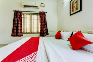 a bedroom with two beds with red pillows and a window at Hotel O J2 Service Apartment in Chennai