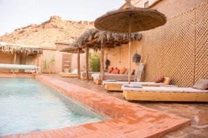 a swimming pool with lounge chairs and an umbrella at Maison d'Hôtes Irocha in Tisseldeï