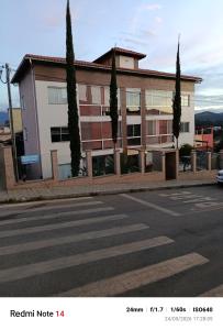 a building with trees in front of a street at Apart Serra Azul in Santa Bárbara