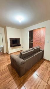 a living room with a couch and a flat screen tv at Apart Serra Azul in Santa Bárbara