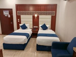 a hotel room with two beds and a blue chair at ALdyar - Al Qunfudhah in Al Qunfudhah