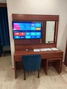a desk with a television and a blue chair at ALdyar - Al Qunfudhah in Al Qunfudhah