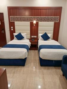 a hotel room with two beds with blue pillows at ALdyar - Al Qunfudhah in Al Qunfudhah
