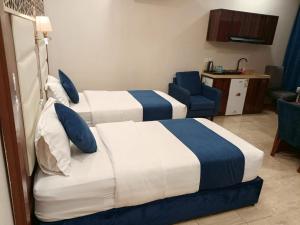 a hotel room with two beds and a blue chair at ALdyar - Al Qunfudhah in Al Qunfudhah