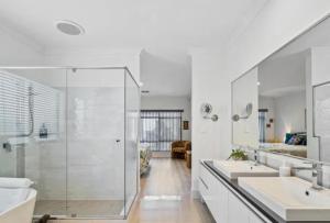 a white bathroom with two sinks and a shower at Seahawk Escape in Mandurah