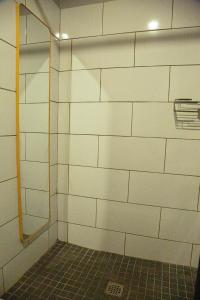 a bathroom with a shower with white tiled walls at The Hideaway Studio-Maboneng in Johannesburg +20 photos