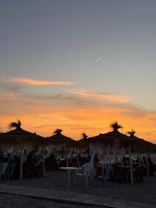 a group of tables and umbrellas on the beach at Maison dar allouche in Kelibia