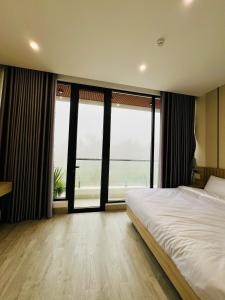 a bedroom with a large bed and large windows at Saka Hotel in Plei Brel (2)
