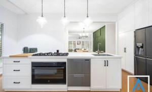 a kitchen with white cabinets and a stove top oven at The Thirlmere Homestead in Thirlmere