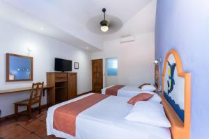 a bedroom with two beds and a desk and a television at Hotel Mexico Lindo in Santa Cruz Huatulco