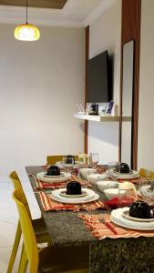 a table with plates and wine glasses on it at Casa com 3 suítes e piscina privativa no centro de Maragogi perto da praia in Maragogi