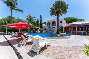 a pool with chairs and umbrellas next to a building at Hotel Mexico Lindo in Santa Cruz Huatulco