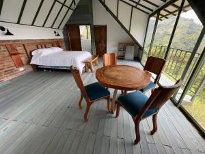 a bedroom with a bed and a wooden table and chairs at La Photinia in Villamaría
