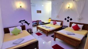 a room with three beds and tables and chairs at Family Nest in Dambulla