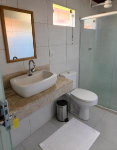 a bathroom with a sink and a toilet and a mirror at Pousada Villa Grauçá in Morro de São Paulo
