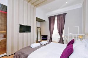 a bedroom with a large white bed with purple pillows at Elegant Suite Vibia 300 mt from Colosseum in Rome