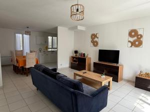 a living room with a blue couch and a tv at La Parenthèse Immo in Amilly