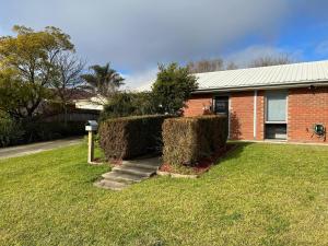 a brick house with two bushes in the yard at 2 bedroom private unit with enclosed back yard in Bairnsdale