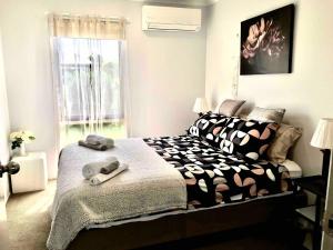 a bedroom with a bed with black and white sheets and a window at 2 bedroom private unit with enclosed back yard in Bairnsdale