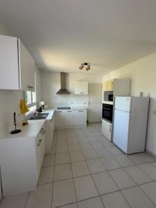 a white kitchen with white appliances and white cabinets at La Parenthèse Immo in Amilly