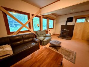 a living room with a leather couch and a table at Wakaranai Lodge Tomamu in Shimukappu