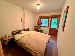 a bedroom with a large bed and a window at Wakaranai Lodge Tomamu in Shimukappu