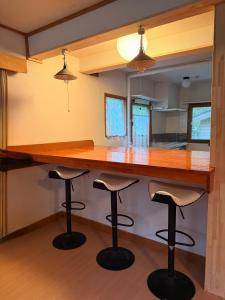 a kitchen with a bar with stools under it at Wakaranai Lodge Tomamu in Shimukappu